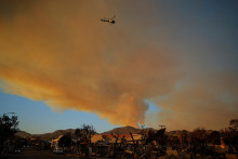Policajný vrtuľník letí nad spálenými oblasťami po požiari Palisades v štvrti Pacific Palisades v Los Angeles. FOTO: Reuters