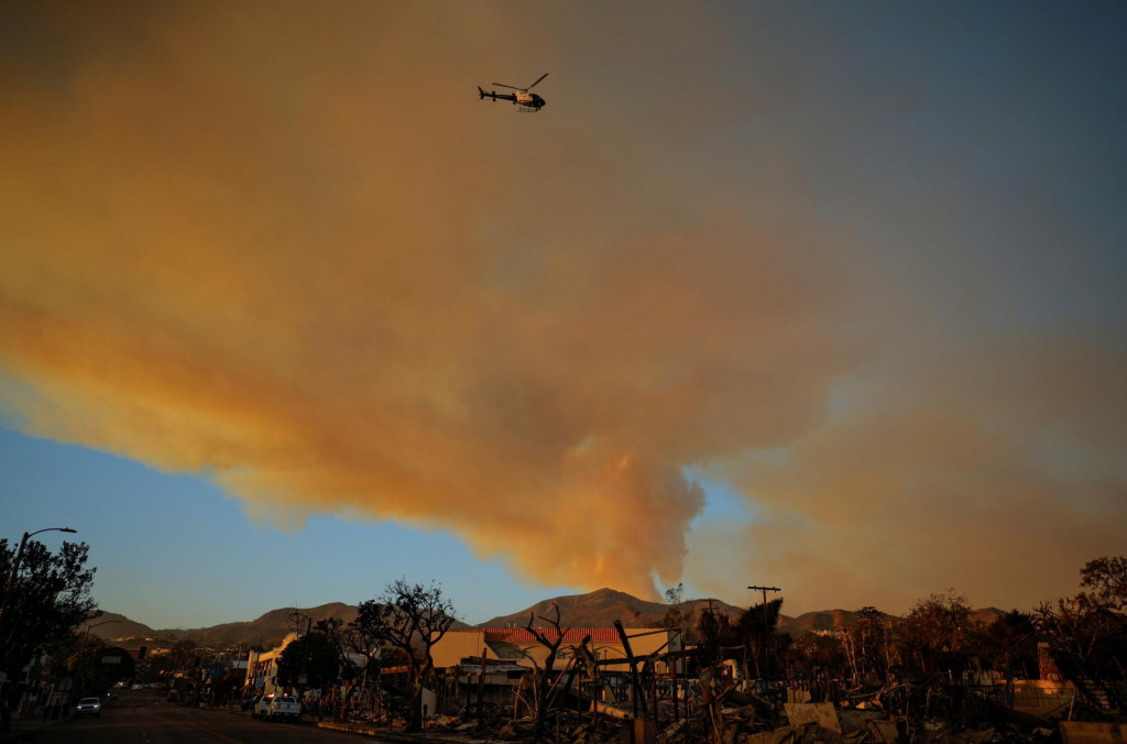 Policajný vrtuľník letí nad spálenými oblasťami po požiari Palisades v štvrti Pacific Palisades v Los Angeles. FOTO: Reuters