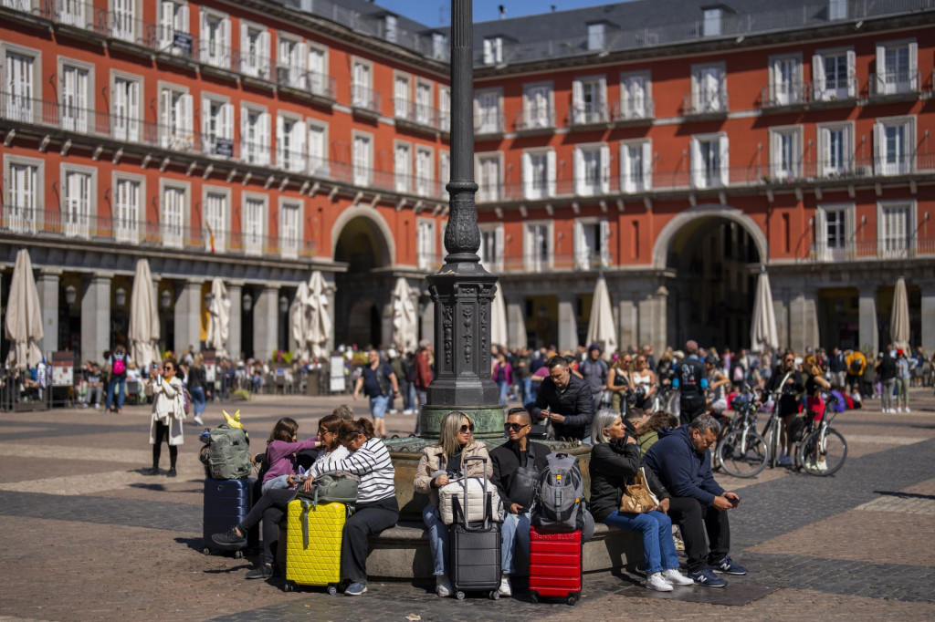 Turisti sedia na lavičke v centre Madridu. Španielsko navštívilo v roku 2024 rekordných 94 miliónov zahraničných turistov. FOTO: TASR/AP