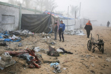 Palestínski chlapci stoja pri poškodenom stane pre vysídlených ľudí po izraelskom nálete v Chán Juníse v južnom Pásme Gazy. FOTO: Reuters