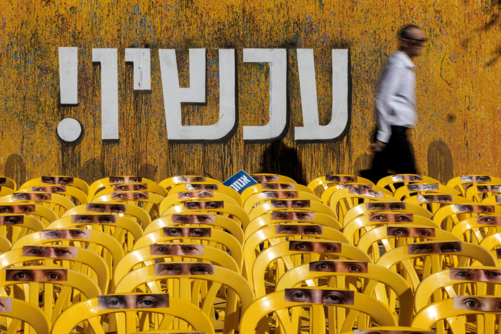 Muž prechádza okolo inštalácie stoličiek s výrezmi obrázkov očí rukojemníkov na takzvanom Námestí rukojemníkov v Tel Avive. FOTO: Reuters