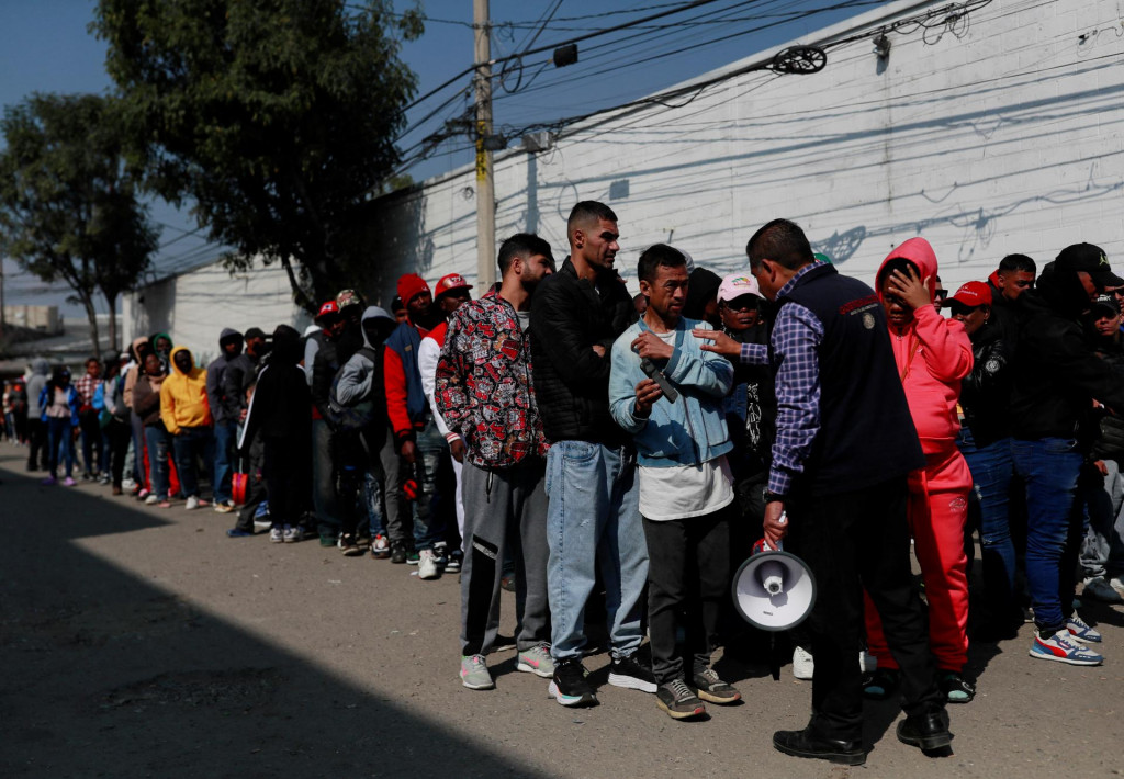 Predstaviteľ Komisie pre pomoc utečencom sa rozpráva s migrantmi mimo Mexickej komisie pre pomoc utečencom, ktorí čakajú v rade na legalizáciu svojej migračnej situácie v krajine. FOTO: Reuters