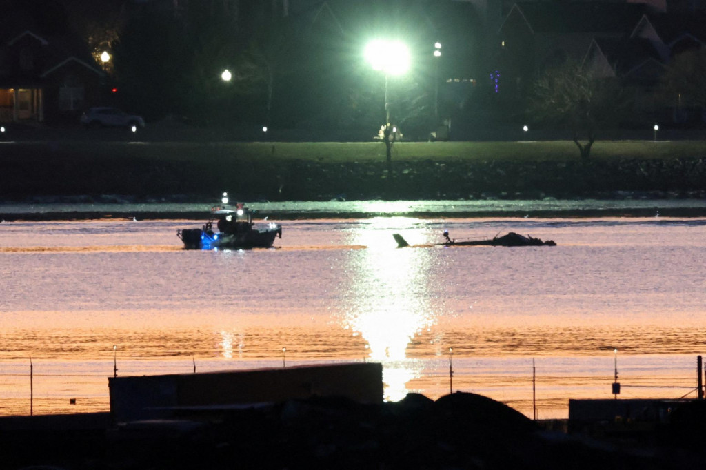 Záchranári na člne pracujú pri troskách vrtuľníka Black Hawk na mieste havárie. FOTO: Reuters