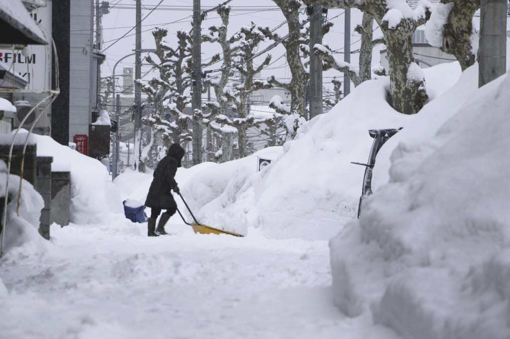 Žena odhrabáva sneh na ulici v meste Aomori na severe Japonska. FOTO: TASR/AP