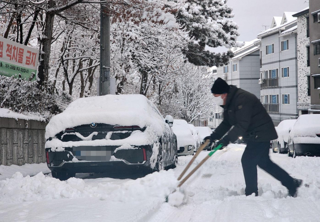 Obyvateľ odhŕňa sneh na ceste počas hustého sneženia v juhokórejskom meste Čondžu. FOTO: TASR/JONHAP