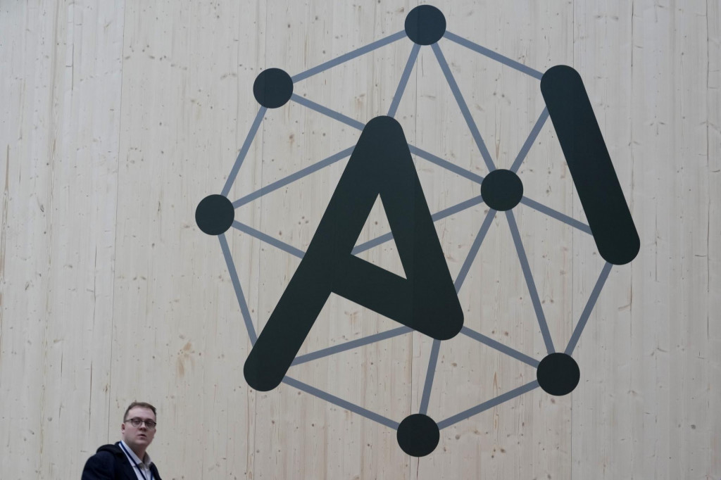 Na snímke účastník kráča okolo loga na summite o umelej inteligencii v Paríži. FOTO: TASR/AP