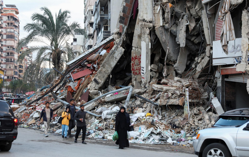 Ľudia kráčajú v blízkosti zasiahnutého miesta na južnom predmestí Bejrútu. FOTO: Reuters
