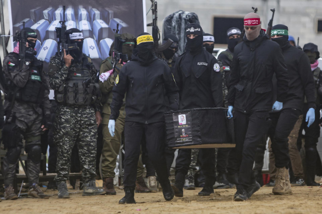 Príslušníci palestínskeho militantného hnutia Hamas prinášajú rakvy s telami štyroch zosnulých izraelských rukojemníkov, ktoré odovzdajú Červenému krížu v meste Chán Júnis na juhu Pásma Gazy. FOTO: TASR/AP