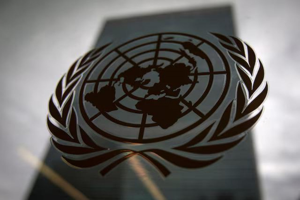 Budova ústredia Organizácie Spojených národov je zobrazená cez okno s logom OSN v popredí v mestskej časti Manhattan v New Yorku. FOTO: Reuters