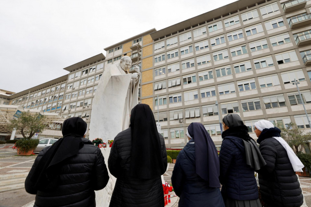 Mníšky sa modlia pred sochou zosnulého pápeža Jána Pavla II. pred nemocnicou Gemelli, kde je hospitalizovaný pápež František. FOTO: Reuters