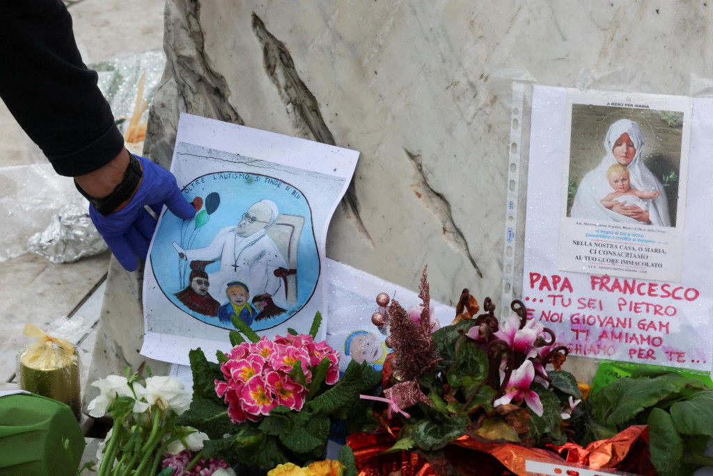 Osoba umiestni obraz pápeža Františka pred nemocnicu Gemelli, kde je pápež František prijatý na ošetrenie v Ríme. FOTO: Reuters