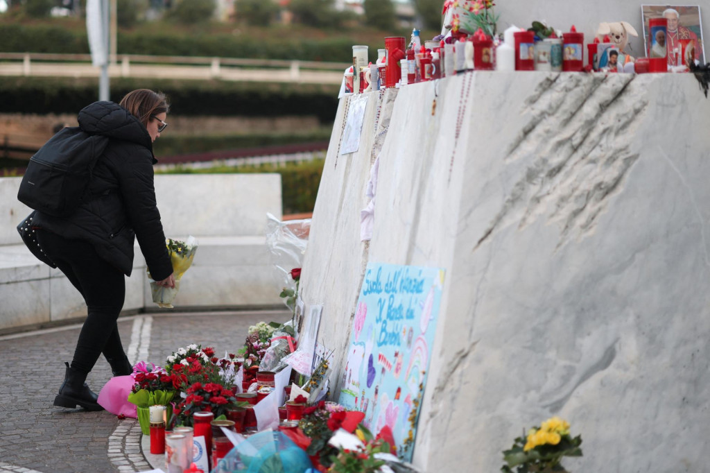 Žena pokladá kvety pred nemocnicou Gemelli, kde je pápež František hospitalizovaný. FOTO: Reuters