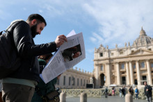 Muž číta noviny na Námestí svätého Petra, zatiaľ čo pápež František pokračuje v liečbe a nebude viesť modlitbu Anjel Pána z okna vo Vatikáne. FOTO: Reuters