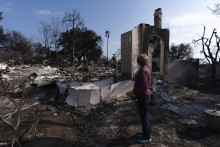 Na archívnej snímke z 30. januára 2025 sa žena pozerá na ruiny svojho domu zničenom požiarom Eaton v kalifornskom meste Altadena. FOTO: TASR/AP