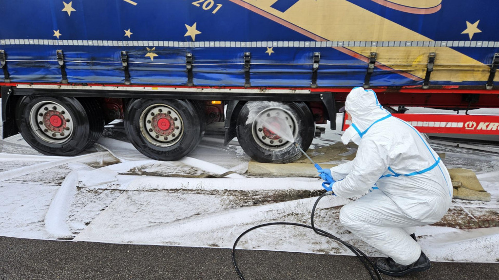Ilustračná fotografia. Pracovník dezinfikuje nákladné vozidlá prichádzajúce na Slovensko z Maďarska na hraničnom priechode Komárno - Komárom. FOTO: TASR/Milan Drozd