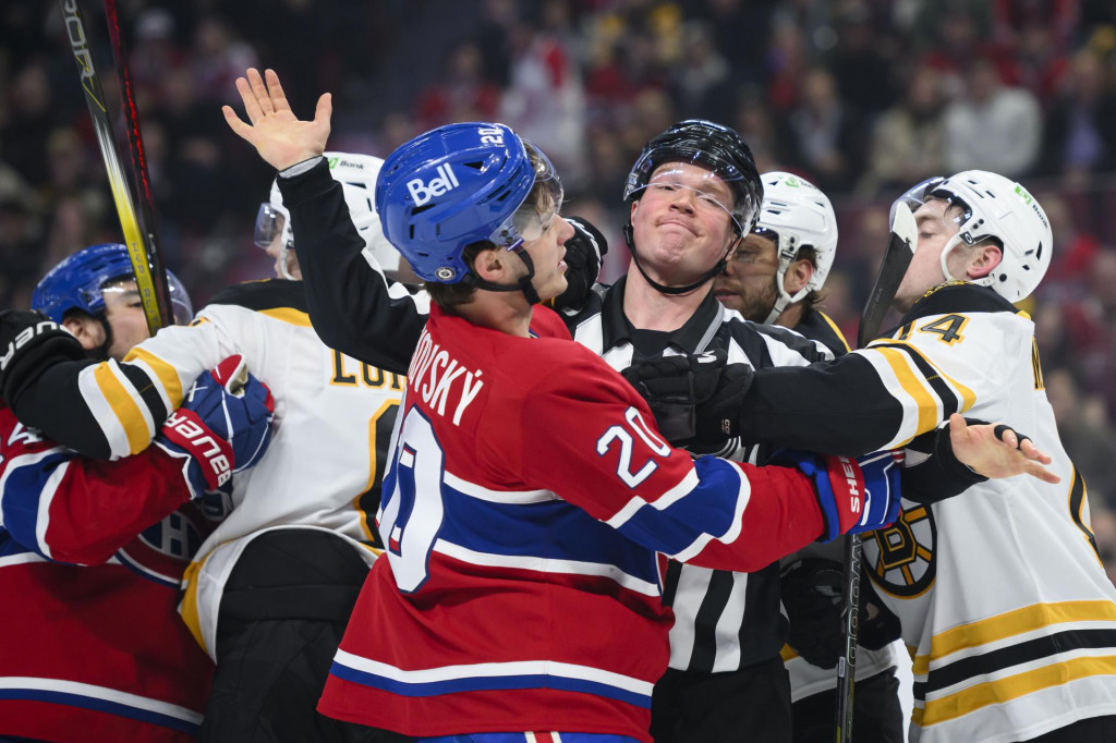 Ľavé krídlo Montrealu Canadiens Juraj Slafkovský a obranca Bostonu Bruins Ian Mitchell v kolízii, uprostred zasahuje rozhodca Jonathan Deschamps. FOTO: TASR/AP