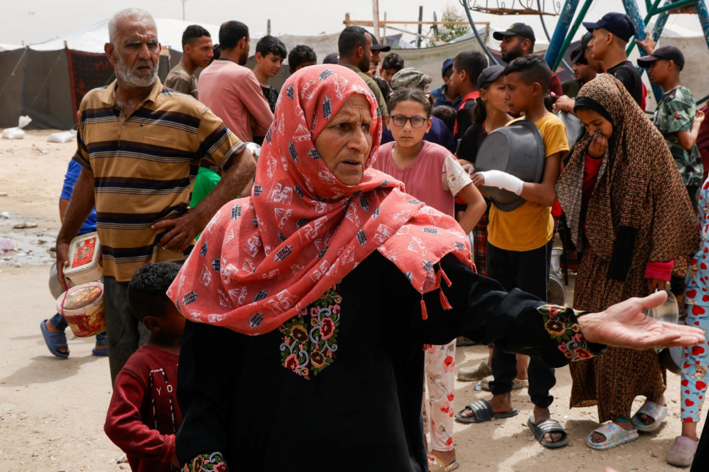 Žena gestikuluje, keď Palestínčania čakajú na jedlo pripravené v charitatívnej kuchyni v Chán Júnise v južnom pásme Gazy. FOTO: Reuters