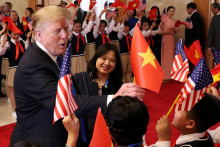 Americký prezident Donald Trump dostáva vietnamskú vlajku, keď ho vítajú študenti v Office of Government Hall v Hanoji, Vietnam, 27. februára 2019. FOTO: REUTERS