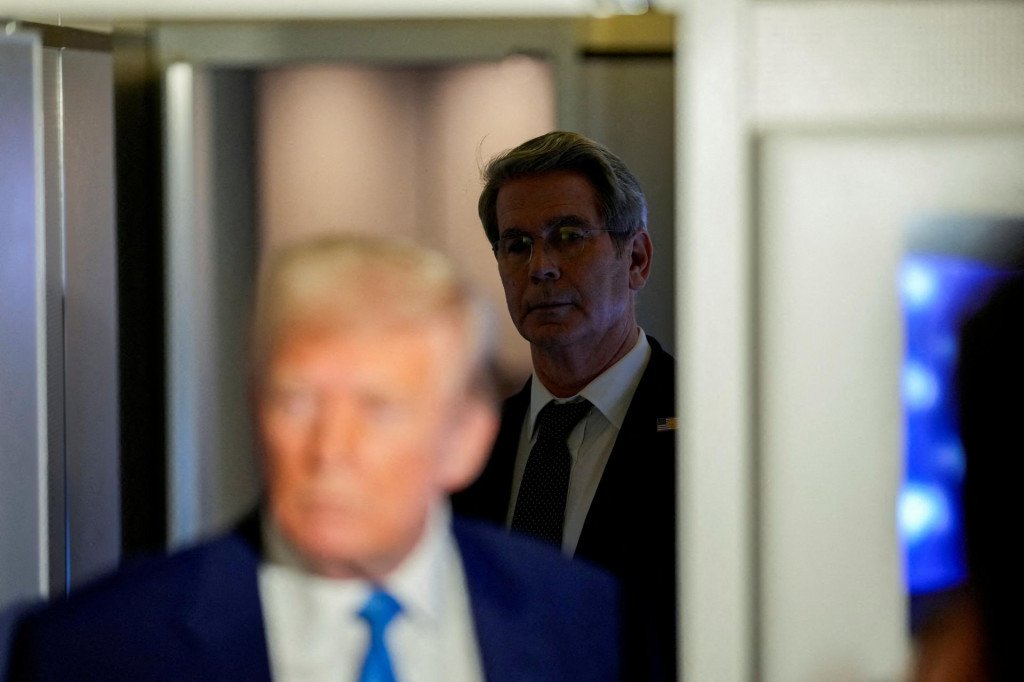 Americký minister financií Scott Bessent sa pozerá na to, ako americký prezident Donald Trump hovorí s novinármi na palube Air Force One počas letu na základňu Andrews, Maryland, USA, 6. apríla 2025. FOTO: REUTERS