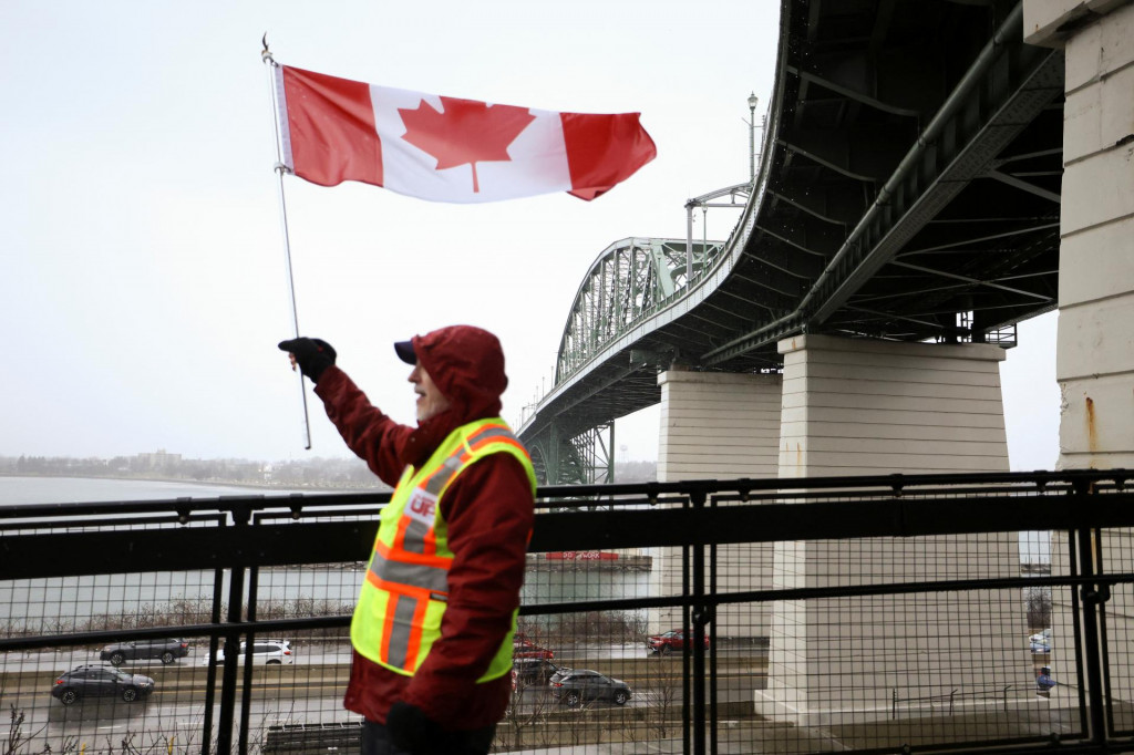Muž drží kanadskú vlajku, zatiaľ čo ľudia protestujú v solidarite s Kanadou uprostred neistoty ohľadom colnej politiky neďaleko kanadsko-amerického hraničného priechodu v Buffale, New York, USA 2. apríla 2025. FOTO: REUTERS