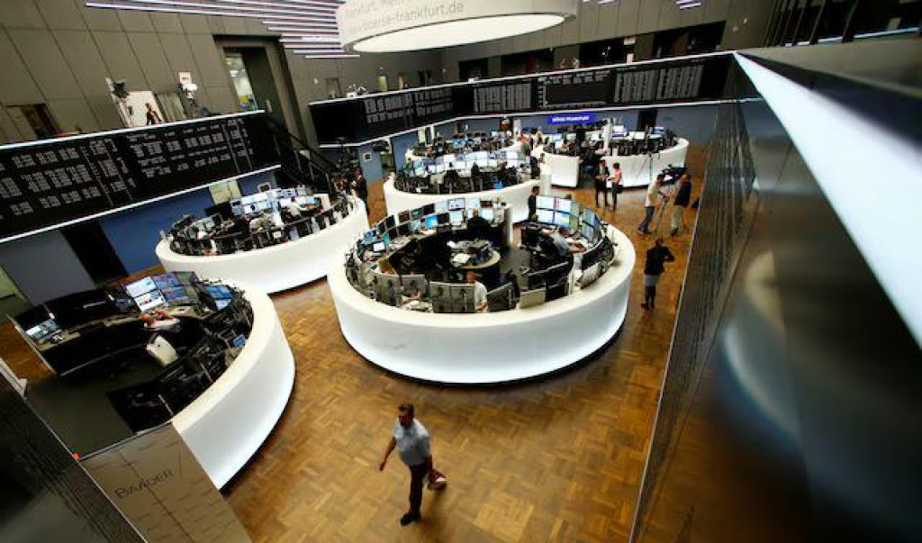Obchodníci pracujú pri svojich stoloch pred nemeckým indexom cien akcií, radou DAX, na burze vo Frankfurte. FOTO: Reuters