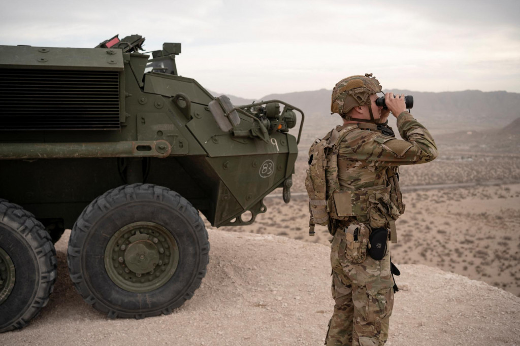 Príslušník národnej gardy USA sa pozerá ďalekohľadom, keď stojí vedľa obrneného vozidla Stryker umiestneného na kopci s výhľadom na americko-mexickú hranicu v Sunland Park v Novom Mexiku. FOTO: Reuters