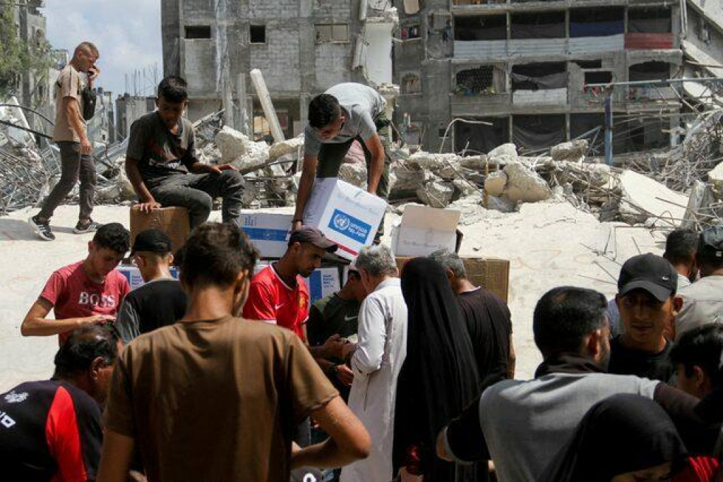 Palestínčania sa zhromažďujú, aby prijali pomoc vrátane dodávok potravín poskytovaných Svetovým potravinovým programom pred distribučným centrom OSN v Džabalii v severnom pásme Gazy. FOTO: Reuters