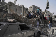 Palestínčania prehľádavajú trosky zničenej obytnej budovy počas izraelského bombardovania Pásma Gazy. FOTO: TASR/AP