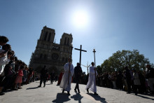 Dobrovoľník nesie kríž počas veľkopiatkového sprievodu „Krížová cesta“ pred parížskou katedrálou Notre-Dame de Paris. FOTO: Reuters