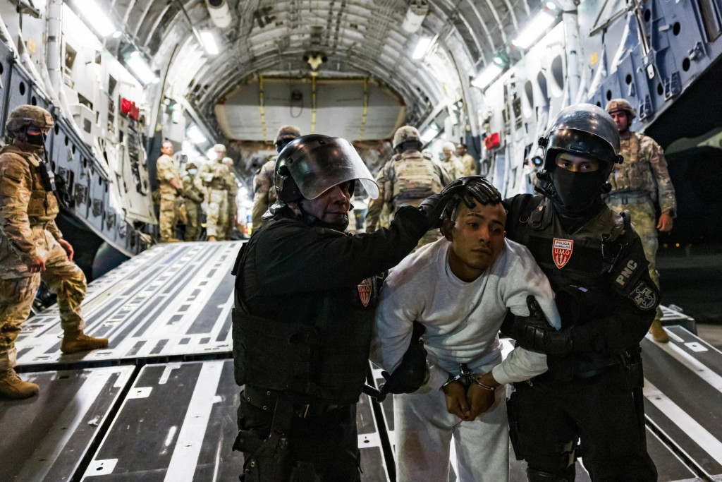 Salvádorskí policajti eskortujú údajného člena gangu, ktorý bol deportovaný USA spolu s ďalšími, o ktorých USA tvrdia, že sú členmi venezuelského gangu Tren de Aragua. FOTO: SECOM cez REUTERS