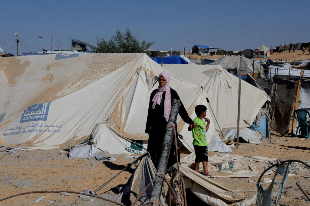 Palestínčania stoja na mieste izraelského útoku na stanový tábor, v ktorom sa ukrývali vysídlené osoby v Chán Júnise na juhu Pásma Gazy. FOTO: Reuters