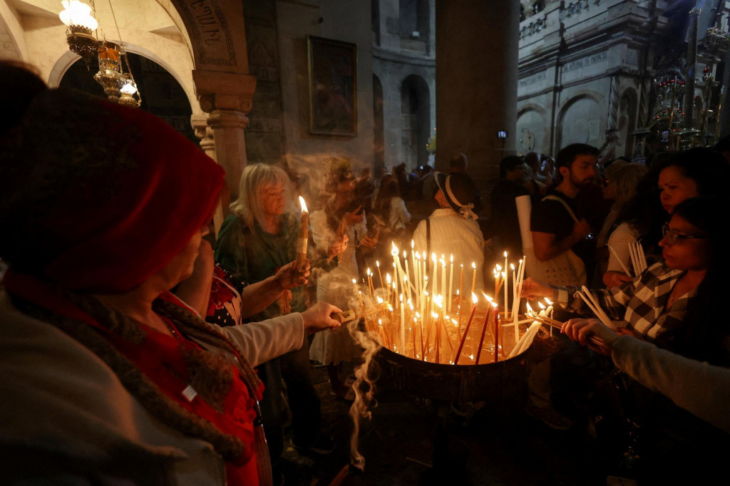 Kresťanskí veriaci zapaľujú sviečky v Bazilike Svätého hrobu v Jeruzaleme. FOTO: Reuters