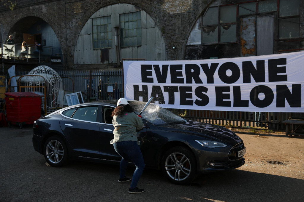 Osoba rozbíja auto Tesla darované anonymne a určené na šrot počas kaskadérskeho kúsku organizovaného skupinou Všetci nenávidia Elona, ​​ktorý je súčasťou kampane proti politickej angažovanosti generálneho riaditeľa Tesly Elona Muska v americkej vláde, v Londýne. FOTO: Reuters