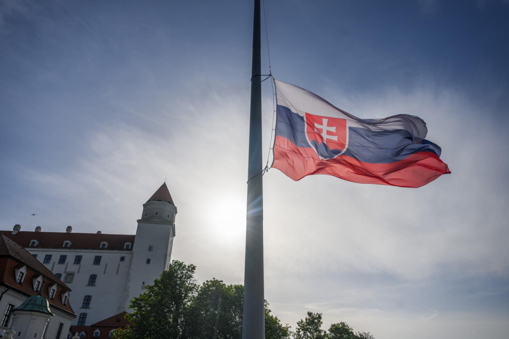Na snímke štátna vlajka Slovenskej republiky (v popredí) je spustená na pol žrde v súvislosti s úmrtím pápeža Františka pred Bratislavským hradom v utorok 22. apríla 2025. FOTO TASR