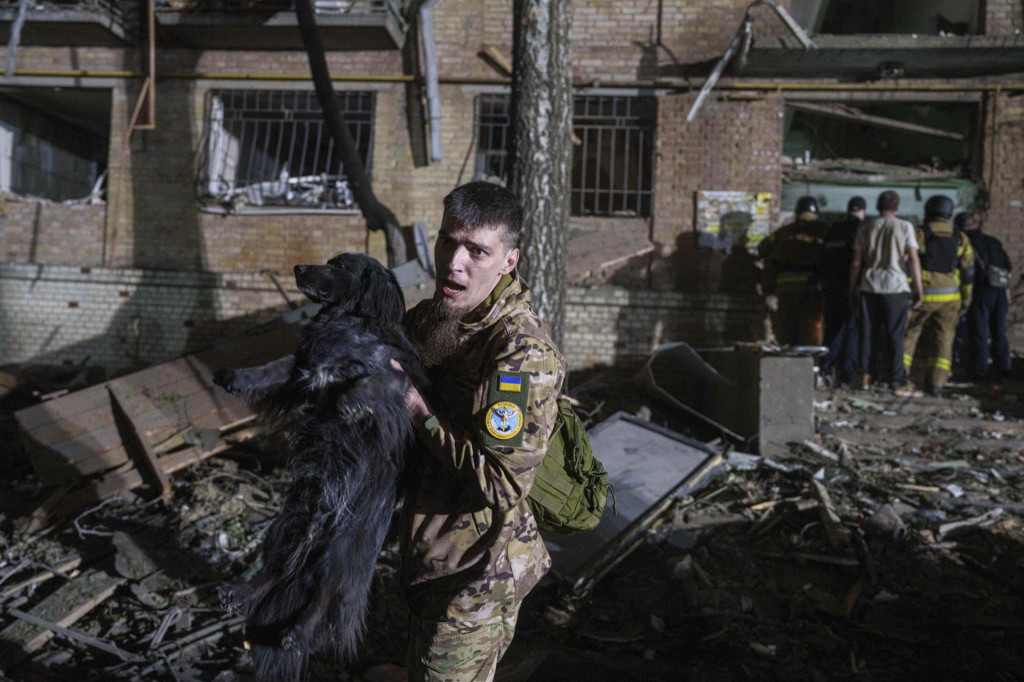 Ukrajinský vojak vynáša psa z domu, ktorý bol zničený po leteckom útoku ruskej armády na obytnú štvrť v Kyjeve. FOTO: TASR/AP