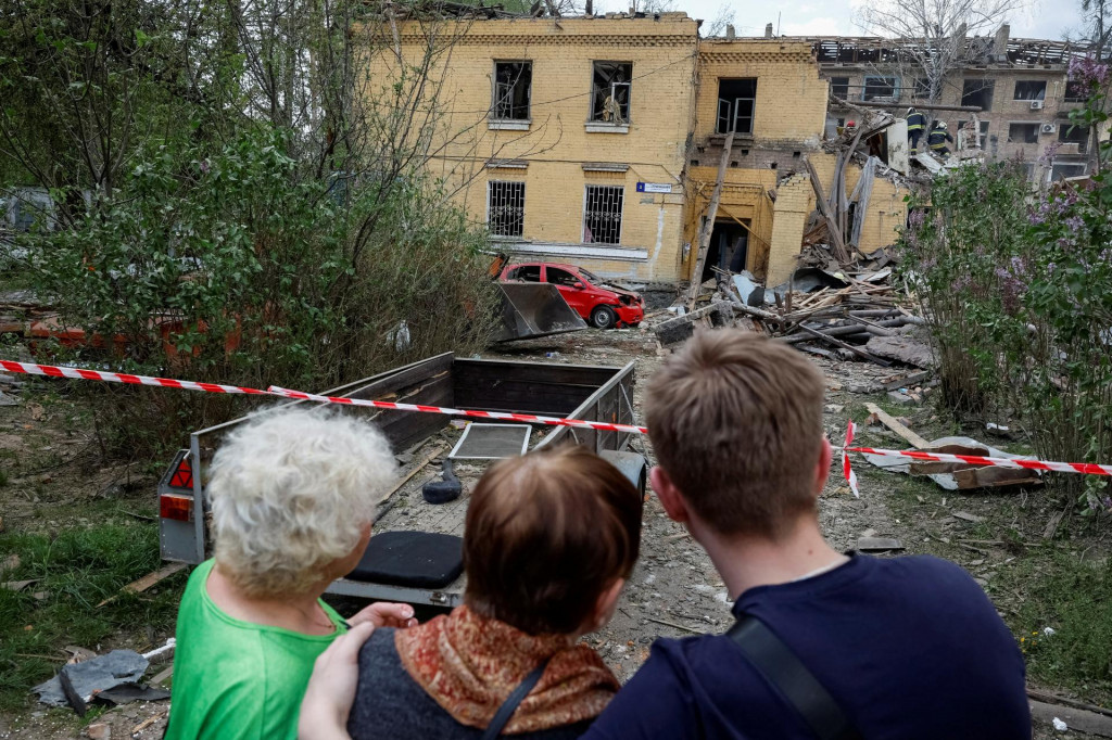 Obyvatelia čakajú na výsledky záchrannej operácie na mieste obytnej budovy poškodenej počas ruského raketového útoku v Kyjeve. FOTO: Reuters