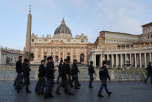 Policajti kráčajú v blízkosti Baziliky svätého Petra pri tom, ako veriaci stoja v rade, aby vzdali úctu pápežovi Františkovi v Ríme. FOTO: Reuters