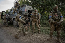 Ukrajinskí vojaci stoja pri vojenskom vozidle uprostred ruského útoku na Ukrajinu. FOTO: Reuters