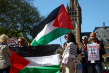 Ľudia držia palestínske vlajky a transparenty pred Medzinárodným súdnym dvorom v deň pojednávania v prebiehajúcom prípade týkajúcom sa izraelskej okupácie palestínskych území v Haagu. FOTO: Reuters