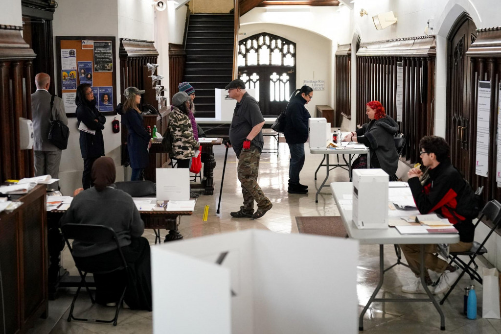 Zamestnanci organizácie Elections Canada pomáhajú voličom vo volebnej miestnosti počas federálnych volieb v Kanade v Toronte. FOTO: Reuters