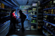 Pracovník pomáha zákazníkovi s baterkou v supermarkete počas výpadku prúdu, ktorý zasiahol rozsiahol Španielsko. FOTO: Reuters