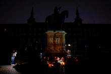 Ľudia sedia pri sviečkach a používajú baterky mobilných telefónov v tme počas celoštátneho výpadku prúdu na námestí Plaza Mayor v Madride. FOTO: Reuters
