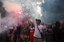 Demonštrant drží dymovnicu počas tradičného prvomájového pochodu odborov v Paríži. FOTO: Reuters