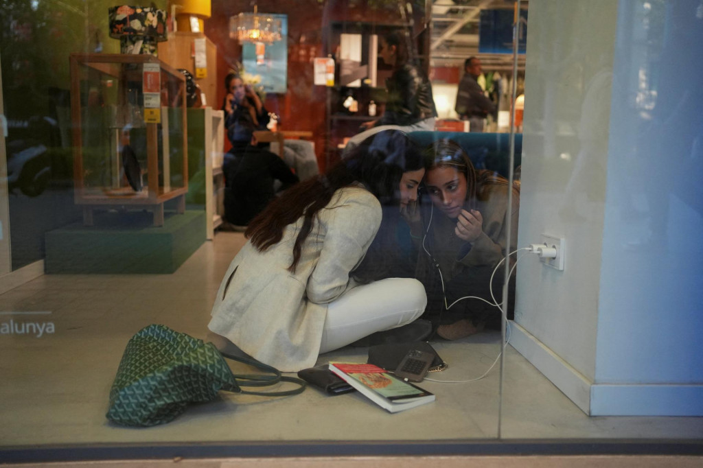 Ľudia používajú wifi a elektrinu v Ikei, kde sa obnovila dodávka elektriny, aby sa počas výpadku prúdu v Barcelone mohli spojiť s rodinou a priateľmi. FOTO: Reuters