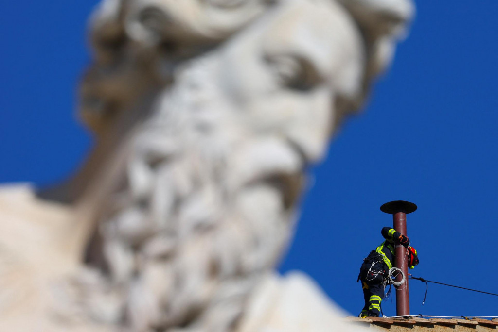 Hasič pracuje na inštalácii komína na streche Sixtínskej kaplnky. FOTO: Reuters