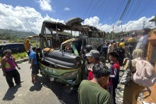 Ľudia si prezerajú vrak autobusu po tom, čo sa vymkol spod kontroly na zjazdovke a prevrátil sa v meste Padang v indonézskej provincii Západná Sumatra. FOTO: TASR/AP