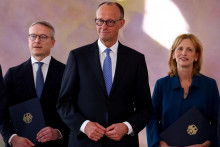 Nemecký kancelár Friedrich Merz sleduje, ako nominovaná nemecká ministerka pre rodinu Karin Prien a nominovaný nemecký minister pre digitalizáciu a modernizáciu štátu Karsten Wildberger držia svoje vymenovacie certifikáty počas slávnostného ceremoniálu v paláci Bellevue v Berlíne. FOTO: Reuters
