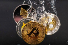 Na tejto ilustrácii sa suvenírové žetóny predstavujúce kryptomenové siete Bitcoin, Ethereum, Dogecoin a Ripple ponárajú do vody. FOTO: Reuters