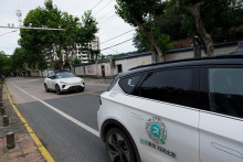 Automobil bez vodiča od spoločnosti Apollo Go, robotickej taxislužby spoločnosti Baidu, prechádza okolo iného robotického taxíka Apollo Go zaparkovaného na kraji cesty v Číne. FOTO: Reuters