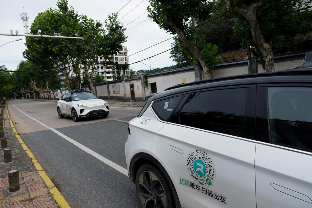 Automobil bez vodiča od spoločnosti Apollo Go, robotickej taxislužby spoločnosti Baidu, prechádza okolo iného robotického taxíka Apollo Go zaparkovaného na kraji cesty v Číne. FOTO: Reuters